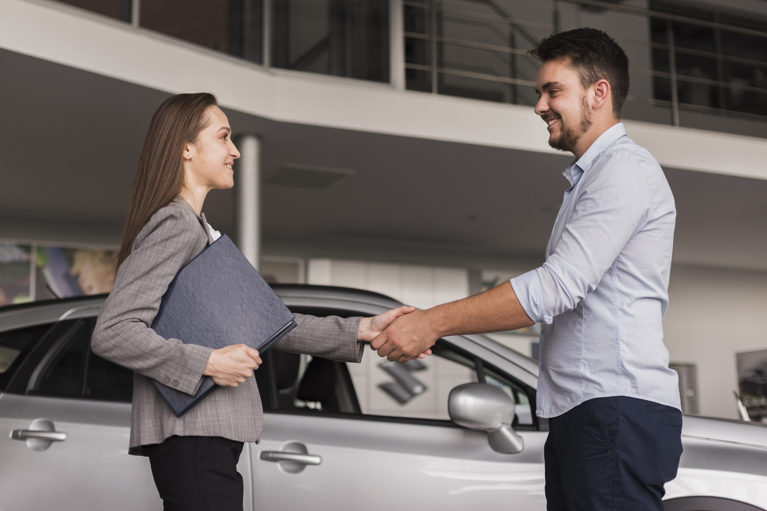 lateral view young man shaking hands with car dealer