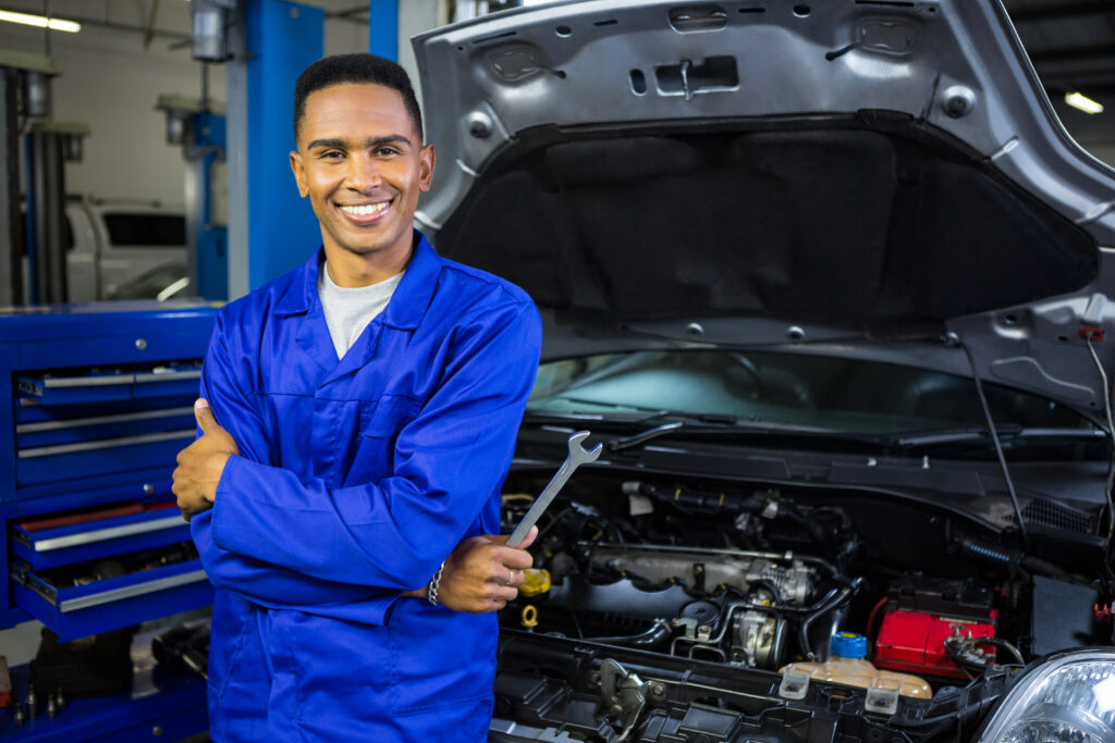 smiling mechanic with arms crossed and spanner